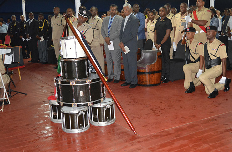 President David Granger; Minister of Public Security, Khemraj Ramjattan, and senior military officers watched as Deputy Commissioner, Paul Williams, draped the GPF and Guyana flags after the piling of the drums. (Rabindra Rooplall Photo)