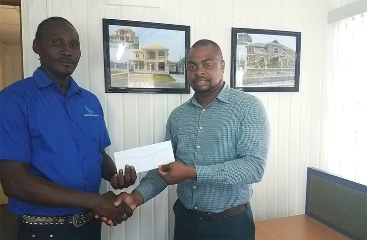 Senior Supervisor at R&D Engineering, Marvin Duke (left), hands over the sponsorship to Edison Jefford yesterday at the company's North Road office.