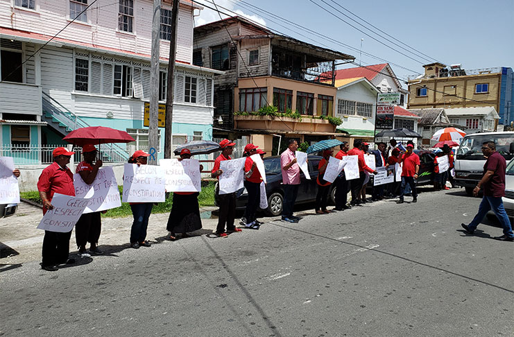PPP protestors standing with placards in front of GECOM’s Church Street, Georgetown office.