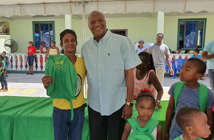 Director General of the Ministry of the Presidency, Joseph Harmon hugs a parent who collected a bag on behalf of his child at the event on Monday.