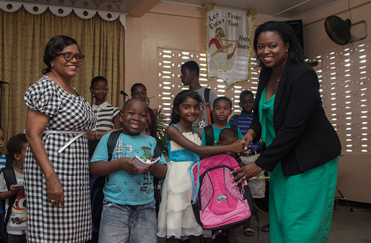 WFC President, Tamara Khan, hands over a backpack to a young girl in Corentyne