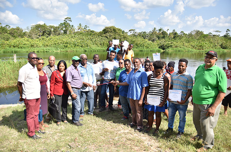 Minister within the Ministry of Social Protection, Keith Scott,(fourth left); CEO of BIT Richard Maughn; BIT Board Chairman, Clinton Williams (fifth left) and  officials from the agency and regional representatives hand over the keys to the boat to community members (DPI photo)