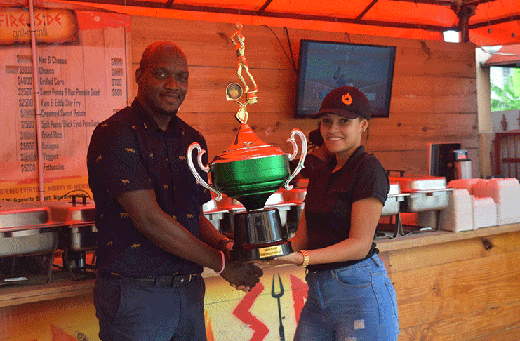 Joanna Collins of FireSide Grill hands over the Most Valuable Player trophy to organiser, Rawle Toney