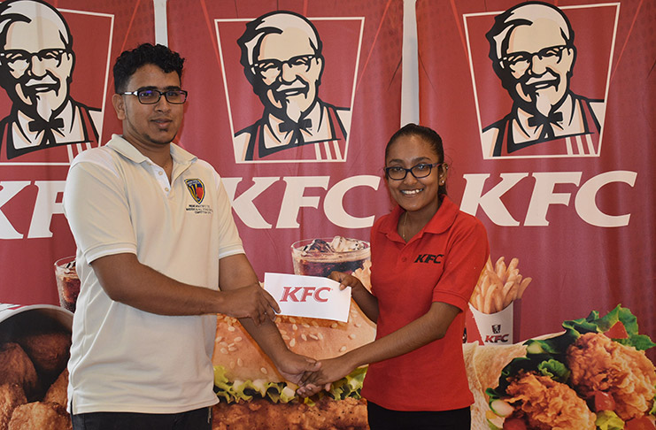 Russell Jubeer (left) receives the sponsorship from KFC’s Senior Accounts Clerk, Oma.