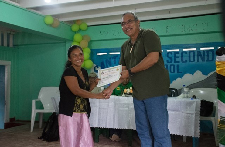 Ministerial Adviser and Member of Parliament, Hon. Mervyn Williams handing over a certificate to one of the beneficiaries