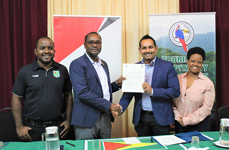 GFF officials Wayne Forde (second left) and Keeran Williams (left) and THAG representatives Mitra Ramkumar (second right) and Treina Butts pose with the document. (Photo: Avenash Ramzan)