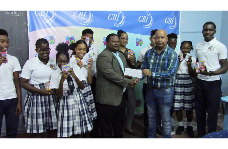 From left, Guyana Beverages Commercial Manager, Samuel Arjune, presents the cheque to Henry Chase with Koolkid Brand Manager Angelina Rodney (centre) and some students of Chase Academy in attendance.