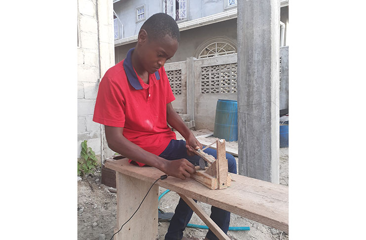 Leroy Austin sawing a piece of wood with a battery operated saw he made