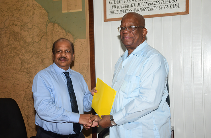 Minister of Finance, Winston Jordan hands over the signed agreement to Governor of BOG, Dr. Gobind Ganga (Adrian Narine photo)