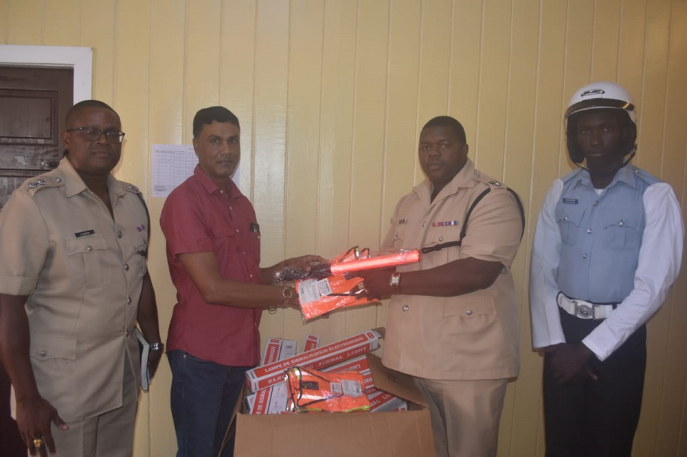 Businessman, Shahab Hack hands over the road safety items to Divisional Commander, Senior Superintendent Kurleigh Simon in the presence of Traffic Officer, Assistant Superintendent, Jermaine Harper and another traffic officer.