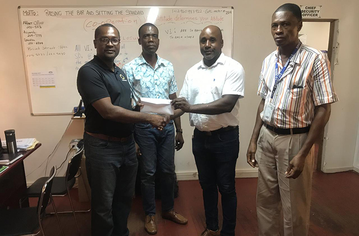 Managing Director of Radar Security Service and Supplies, Mr. Adepemo Peters (2nd right) hands over sponsorship to GFF President, Wayne Forde in the presence of two employees.