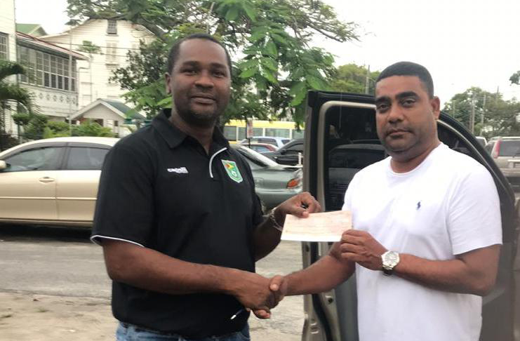 General Manager of SleepIn Hotel, Clifton Bacchus, (right) hands over the sponsorship cheque to GFF president Wayne Forde.