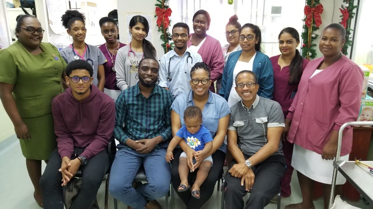 Jasmin Harris-Smith (sitting second from right) with baby Jedidiah Smith; her husband, Brian, (third from right) with other family members and staff of the GPHC NICU