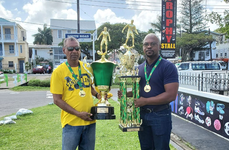 Ramesh Sunich proprietor of ‘Trophy Stall’ presents the first place trophy to president of the Upper Demerara Football Association (UDFA) Terrence Mitchell.