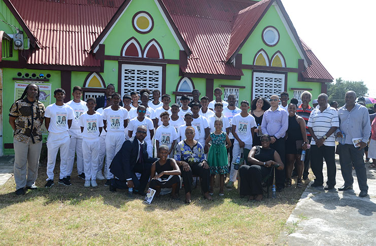 Mrs Pamela Butcher carrie the ashes and family pose with the young Berbice cricketers who honoured her husband.