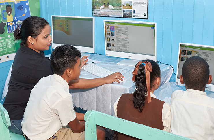 At left: Pomeroon Trading’s Community Development Coordinator, Tana Yussuff, in the new library and computer centre with pupils operating the computers