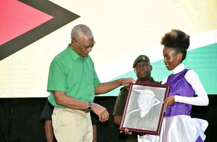 Roxanne Austin presenting President David Granger with a portrait of himself at the Victoria Village Day event in November