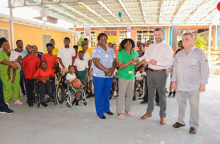 Administrator of the Ptolemy Reid’s Rehabilitation Centre, Cynthia Massay, receives the $5M cheque from Stena Drilling Rig Manager, Nick Benzie in the company of other officials, while some of the staff and children at the rehabilitation centre look on (Delano Williams photo)