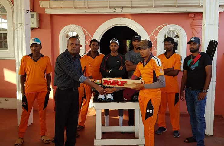 Here, Persaud (left) hands over part of the donation to Mohabir while other members of the club look on.