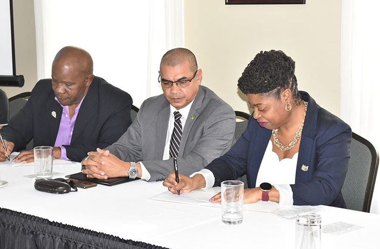 Minister of Business, Haimraj Rajkumar, watches on as Stacey Mollison of the Guyana Georgia Tourism and Business Authority and Donald Sinclair of the Department of Tourism sign the Memorandum of Understanding