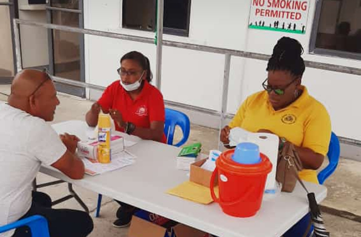 Health workers screening a patient at the Suddie Hospital before he enters the medical facility