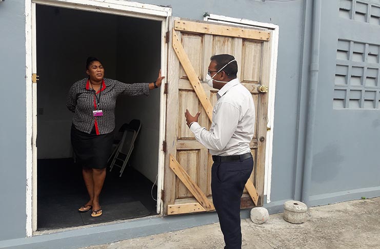 Regional Environmental Health Officer Marvin Dindyal informing a Funeral Home Operator in New Amsterdam of the new guidelines