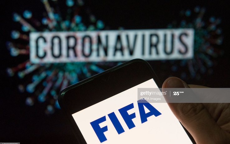 In this photo illustration the Fédération Internationale de Football Association (FIFA) logo seen displayed on a smartphone with a computer model of the COVID-19 coronavirus on the background. (Photo Illustration by Budrul Chukrut/SOPA Images/LightRocket via Getty Images)