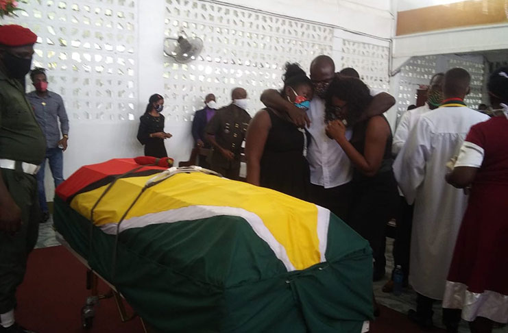 The late Lance Corporal Kevon Nicholson’s siblings comfort each other as they gaze at the unopened casket bearing the remains of the baby of the family