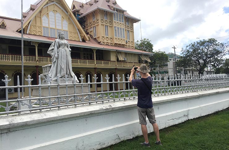 English tourist taking a photograph of the Queen Victoria statue in the forecourt of the High Court in Georgetown (Photograph by Francis Q. Farrier, February 2020)