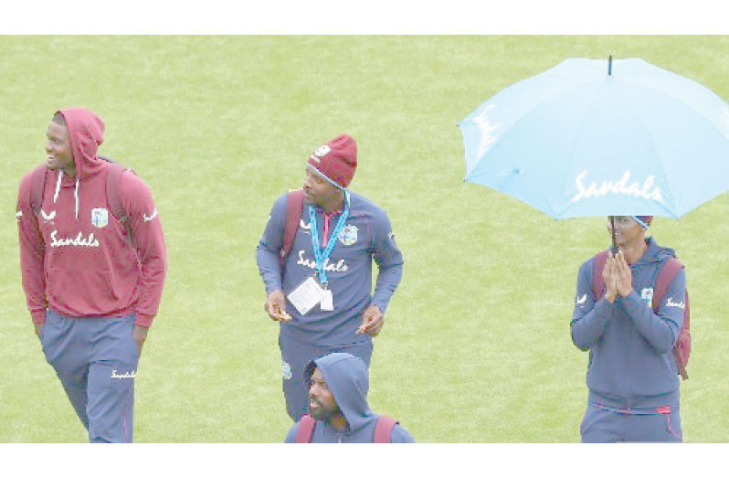 West Indies players stroll across the field at Old Trafford during the rain delay.