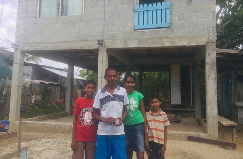 Manny Ram and his wife along with two of his three children stand in front of their incomplete house