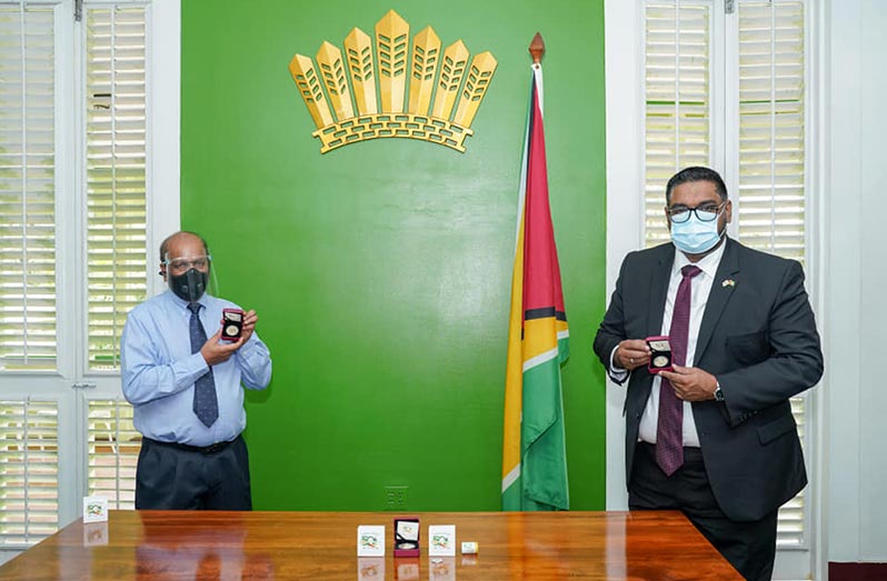 President Irfaan Ali and Dr. Gobin Ganga, Governor of the Bank of Guyana show off the two commemorative coins at State House on Monday morning