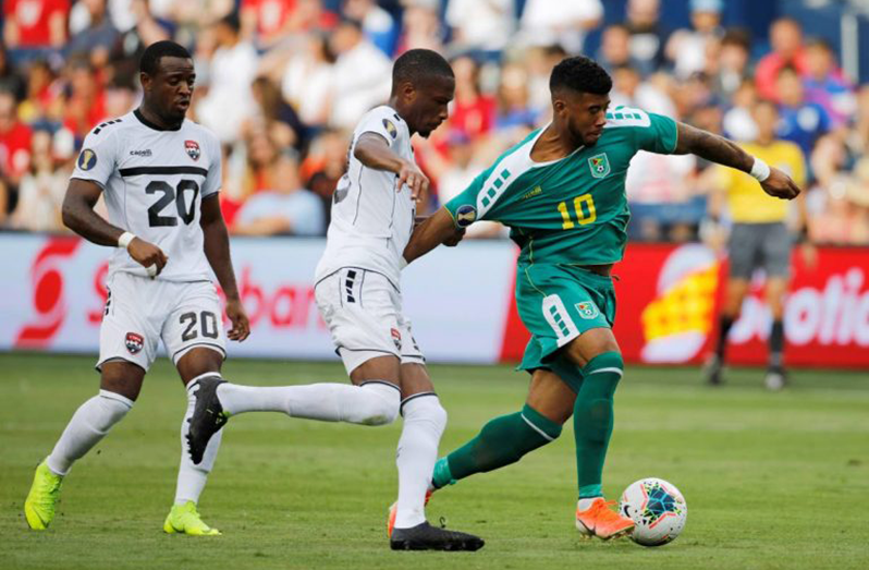 Guyana's Emery Welshman (#10) bullying his way against Trinidad defender Curtis Gonzales during their clash which ended 1 - 1 at the 2019 CONCACAF Gold Cup. (PHOTO CREDIT: Associated Press)