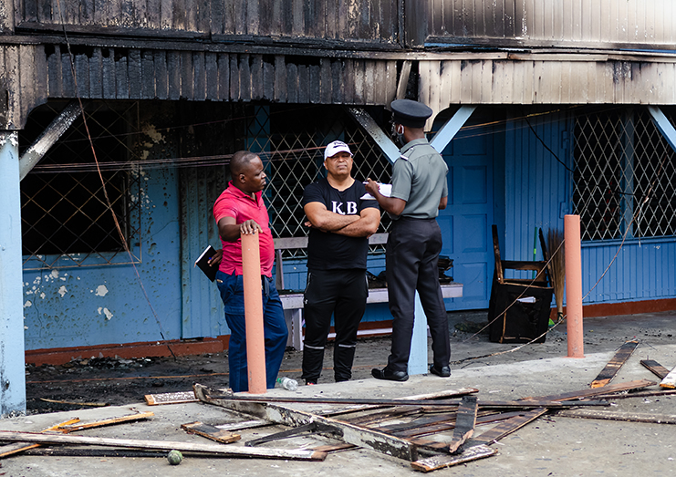 Mr. Henry Chase, founder and principal of Chase’s Academy (centre),  speaking with Guyana fire service investigators, following the fire (Photos by Delano Williams)