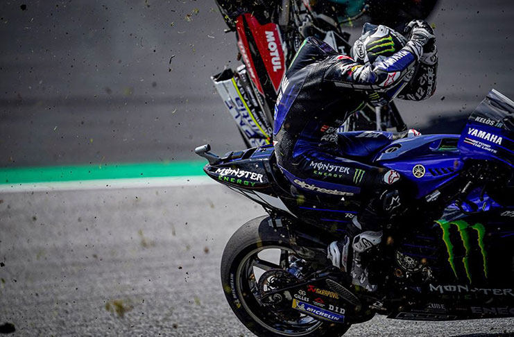 Maverick Vinales ducks under the flying wreckage of one of the two bikes