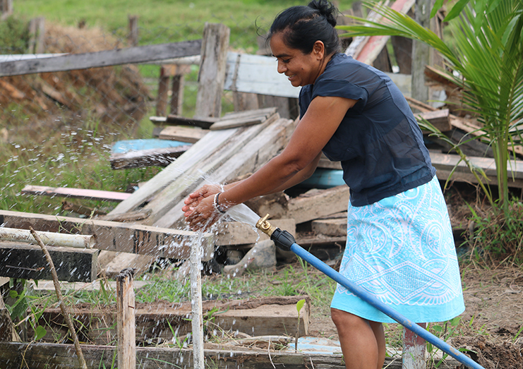 Seeta Sookram, a happy resident of the Canal Number One  Conservancy area, turns on the pipe which now gives potable water