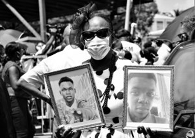 Cousin of Joel and Isaiah, former Education Minister, Dr. Nicolette Henry, holds up photos of the slain boys (Carl Croker photo)