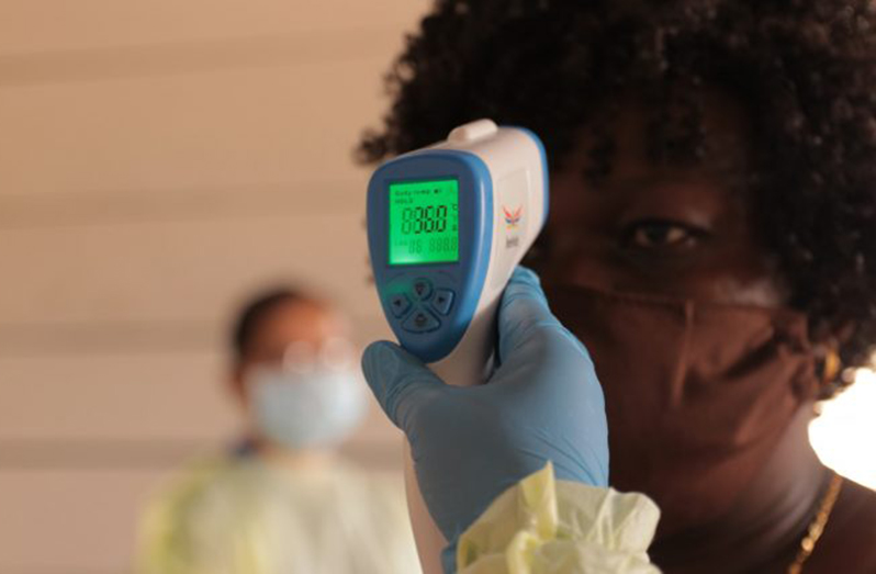 Health Officials check the temperature of a Guyanese citizen (Ministry of Health photo)