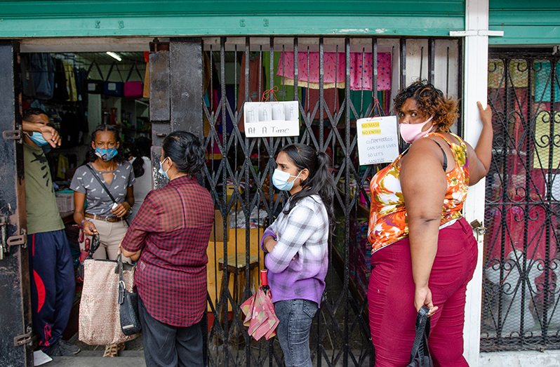 Young persons wearing their masks and maintaining some distance as they shop on Regent Street, Georgetown (Delano Williams photo)