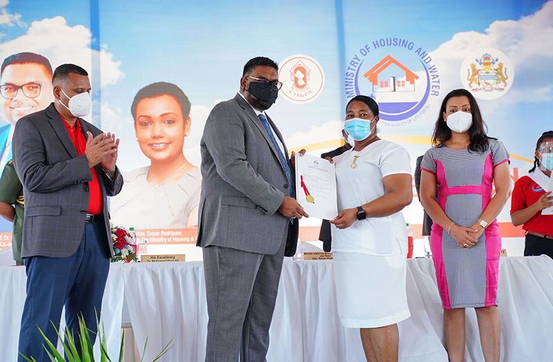 President Dr. Irfaan Ali hands over title and transport to one of the first five persons at the ‘Dream Realised Housing Drive 2020’ held at the Providence National stadium, East Bank Demerara.  Housing Ministers Collin Croal and Susan Rodrigues look on (OP Photo)