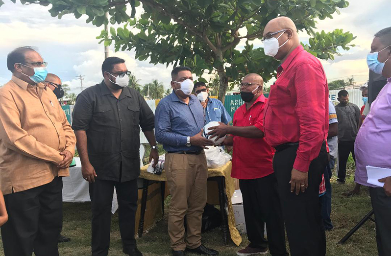 Agriculture Minister Zulfikar Mustapha hands over a football and other sports gear to an Angoy’s Avenue club representative as President Dr Irfaan Ali; Minister within the Ministry of Local Government, Anand Persaud; and Public Works Minister Juan Edgill and others look on