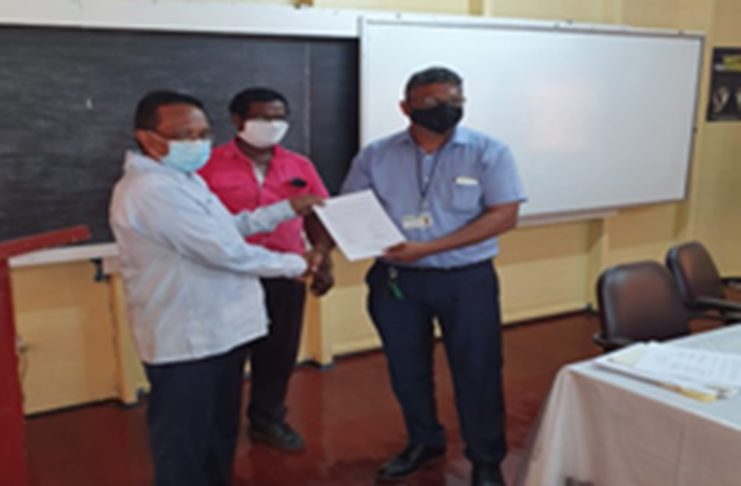 GuySuCo Chief Industrial Relations Manager, Deodat Sukhu handing over the signed agreement to GAWU’s General Secretary, Seepaul Narine