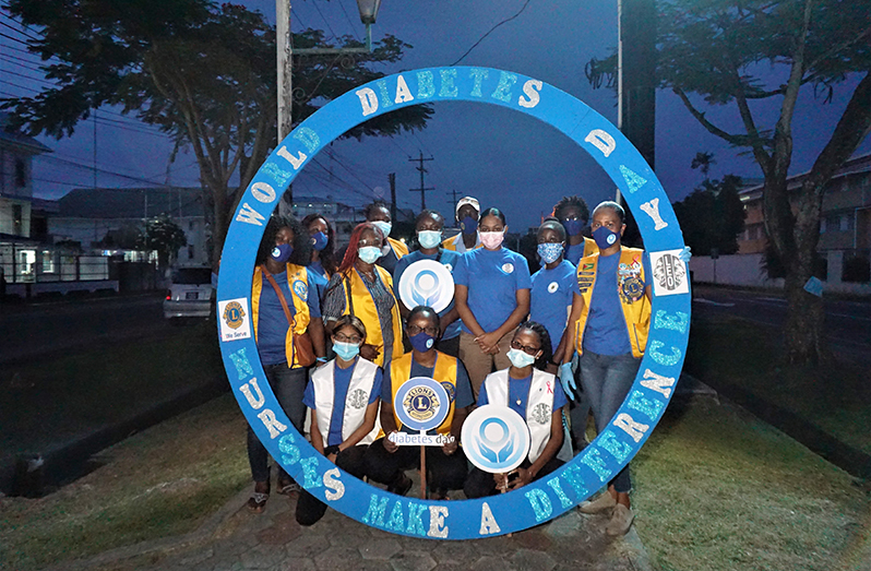 Members of the Leo and Lions Clubs who participated in the activity show off the blue circle they erected in the avenue on Camp Street