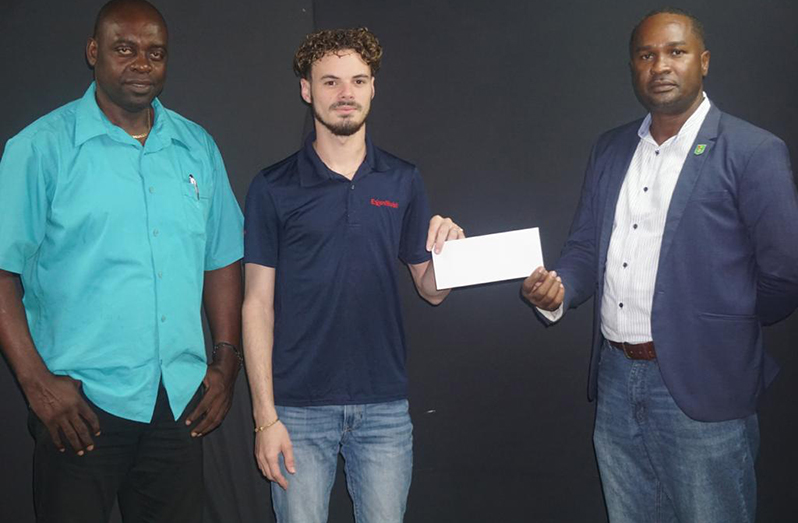 GFF president Wayne Forde collects sponsorship from Nicholas Yearwood, Communications Manager of ExxonMobil, in the presence of K&S director Aubrey Major.