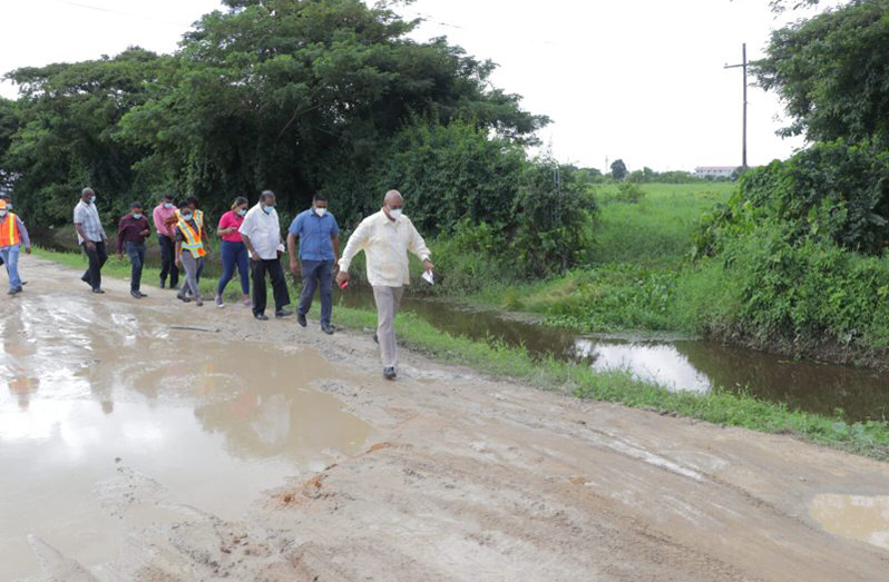 Public Works Minister, Bishop Juan Edghill; Local Government and Regional Development Minister, Nigel Dharamlall and team navigate the road parallel to UG