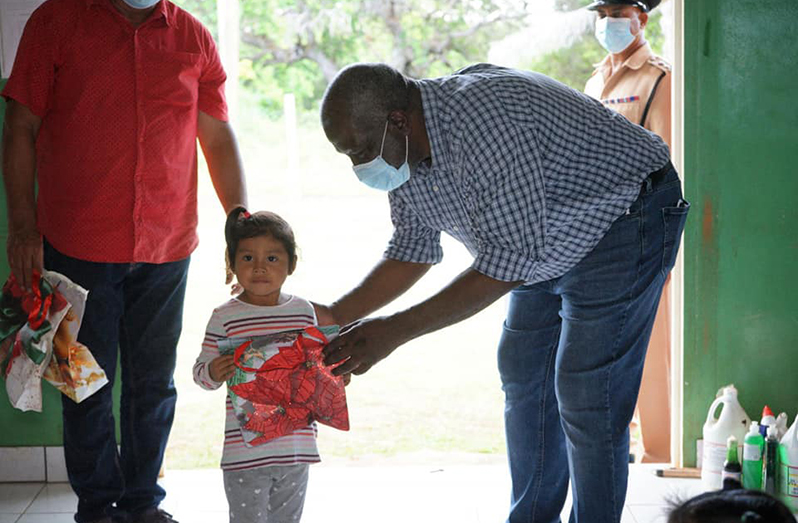 Prime Minister Phillips gifts a child in an outlying village a Christmas package during the outreach