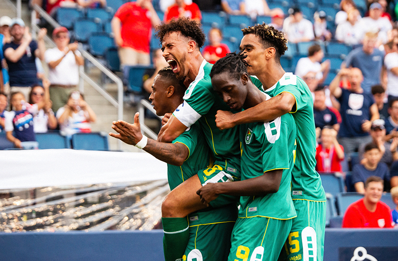 PICTURE PERFECT! Neil Danns was swarmed by his Golden Jaguars teammates (Sam Cox, Sheldon Holder and Terence Vancooten) after scoring a beautiful goal to give Guyana a 1-0 lead over T&T in the CONCACAF Gold Cup. (Samuel Maughn photo)