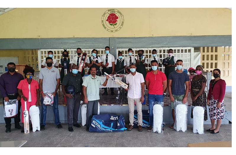 Former Guyana and West Indies cricketer Shivnarine Chanderpaul (fifth from right) presents a bat to Headmaster of the West Demerara Secondary School, Harrinarine. Sharing the moment are teachers, students and cricketers Tagenarine Chanderpaul (third right), Akshaya Persaud (fourth right) and local Almuni representative Naveed Ali (third left).