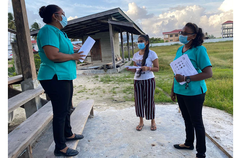 A youth being sensitised about the upcoming campaign by Regional Coordinator, Shaleena Baksh, and pill distributor, Roseanne Latchman, at Golden Fleece community ground