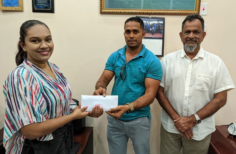 Proprietor of Mohamed’s Enterprise Nazar Mohamed (right) looks on as one of his staff hands over sponsorship cheque to Telesha Ousman.